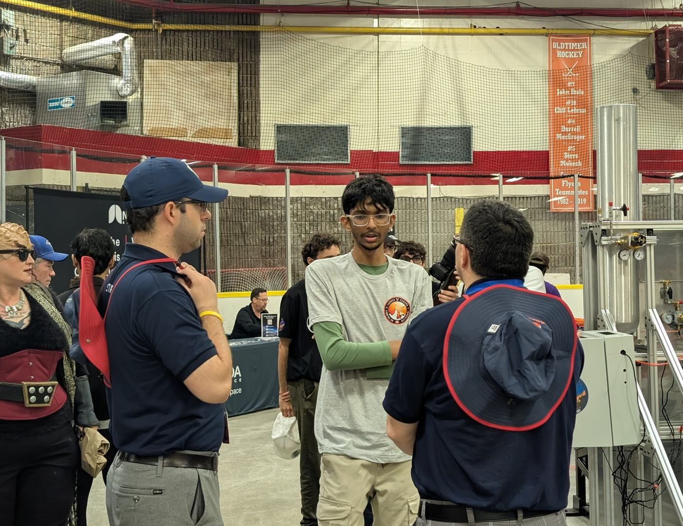 A member in a team shirt talking with people at the conference hall