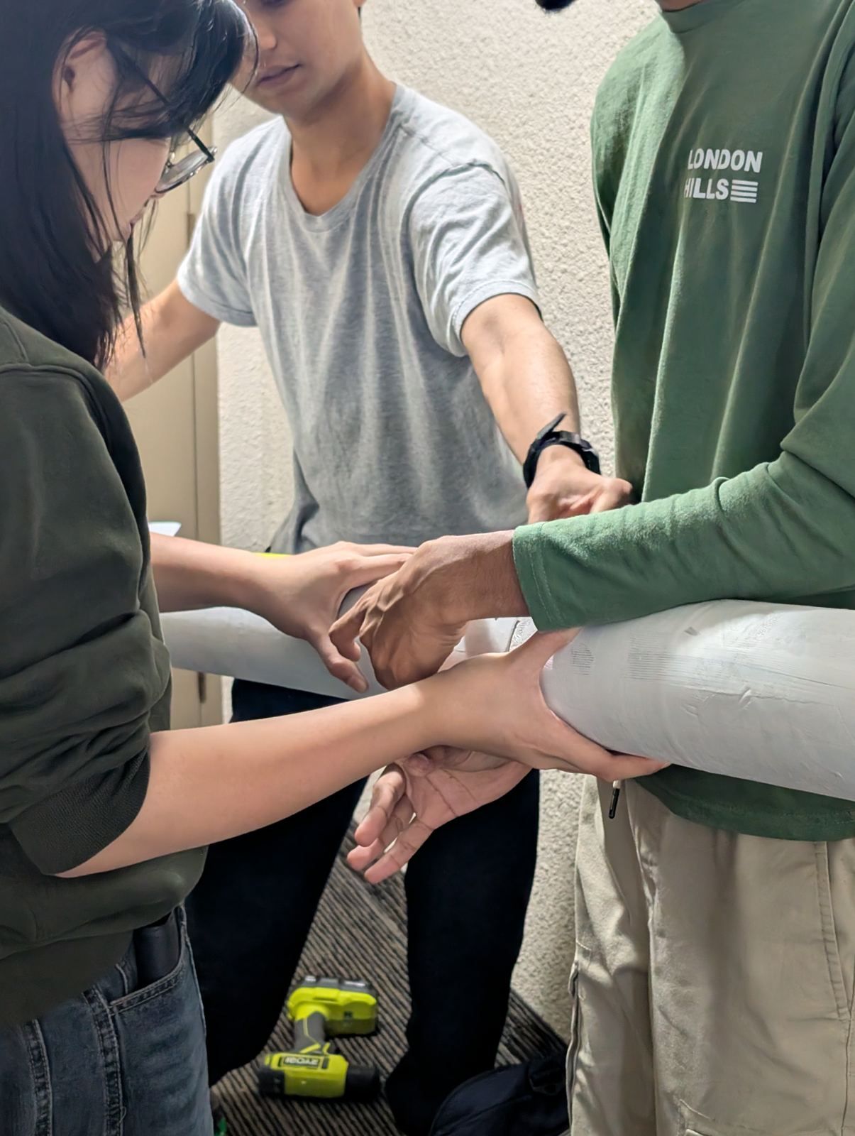 Three team members holding two airframe sections together for a fit check