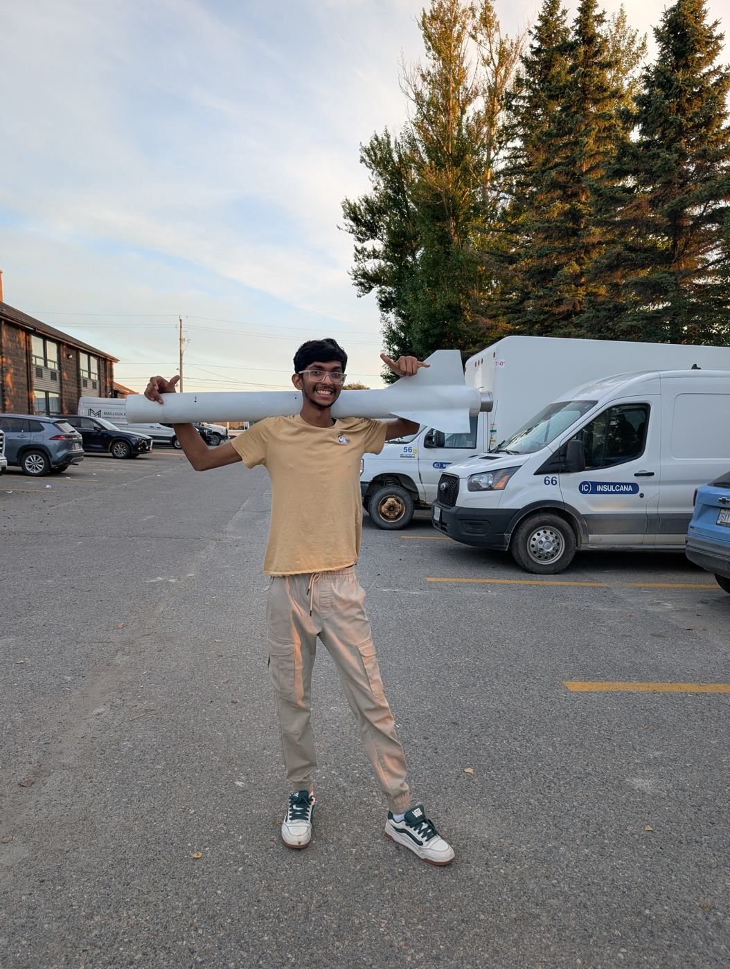 A member carrying an airframe tube on his shoulders in a parking lot
