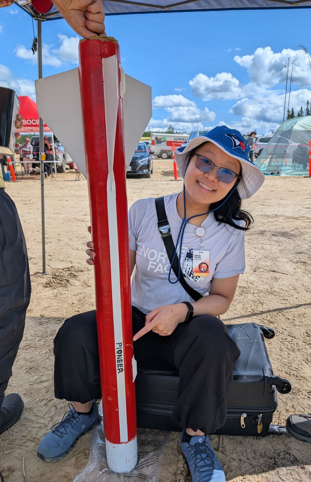 A team member sitting beside Pioneer, pointing to the PIONEER lettering on the airframe